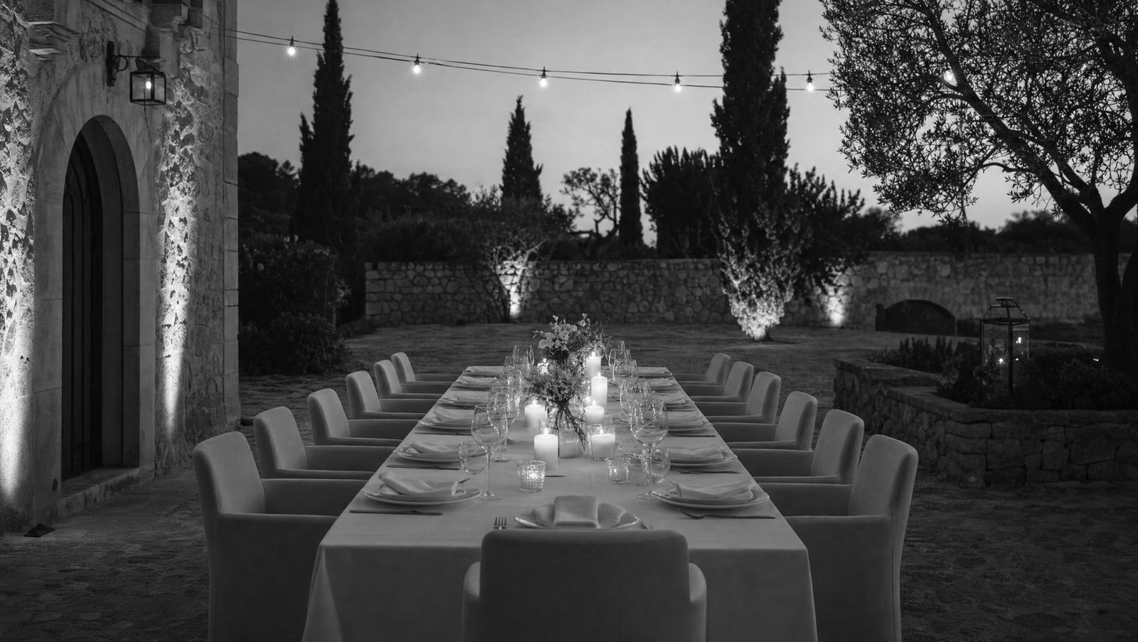 Eine lange, festlich gedeckte Tafel im Garten am Abend